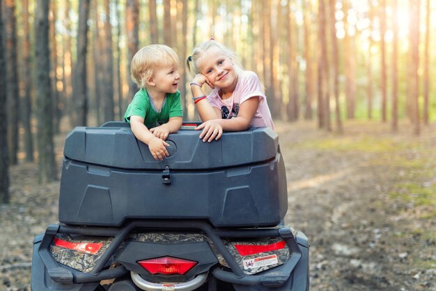 Niña con hermano en quad en el bosque