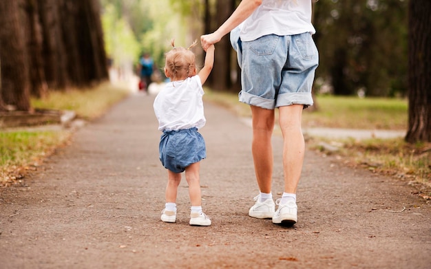 Niña hermosa camina en el parque con su mamá