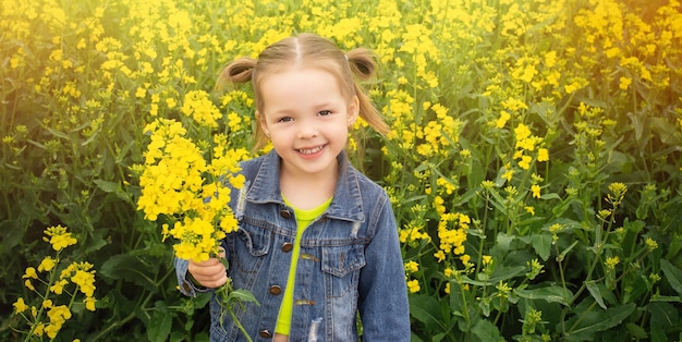 una niña hermosa en un campo de colza la sonrisa de un niño en un día de verano una pancarta fotográfica