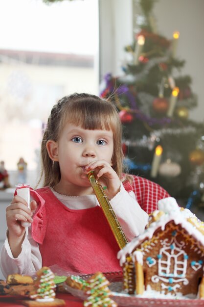 Niña hermosa con una casa de masa de pan de jengibre