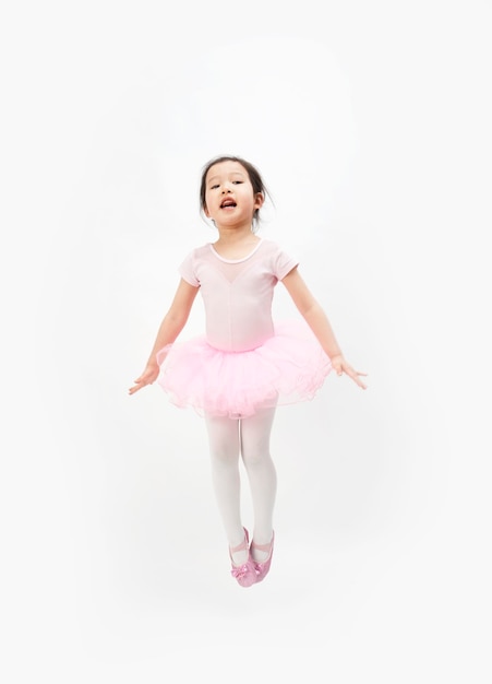 La niña hermosa está haciendo gimnasia en un fondo blanco