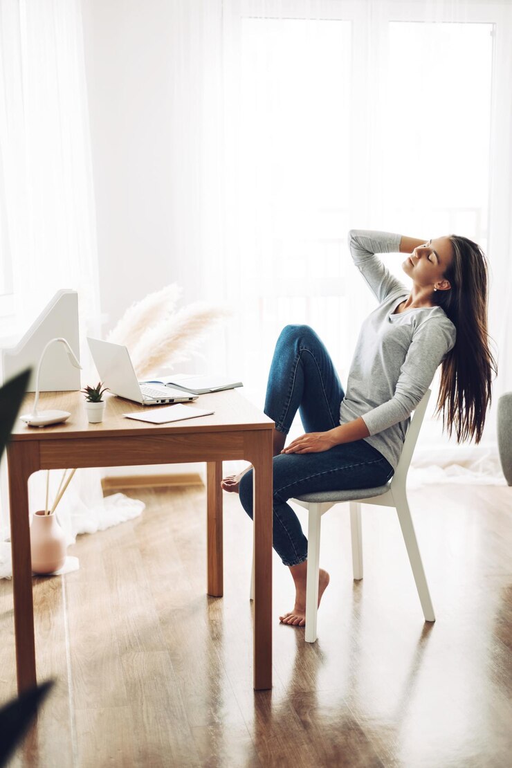 Foto una niña hermosa está sentada reclinada en una silla y estirándose después del trabajo en una computadora portátil