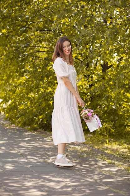 Niña hermosa con flores en un vestido gafas y zapatillas de deporte