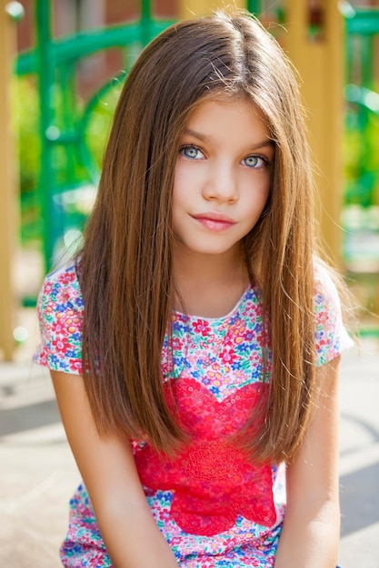 Una niña hermosa en el fondo verde del parque de la ciudad de verano.