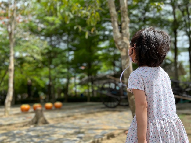 Foto una niña hermosa mira un árbol lejano con espacio para copiar