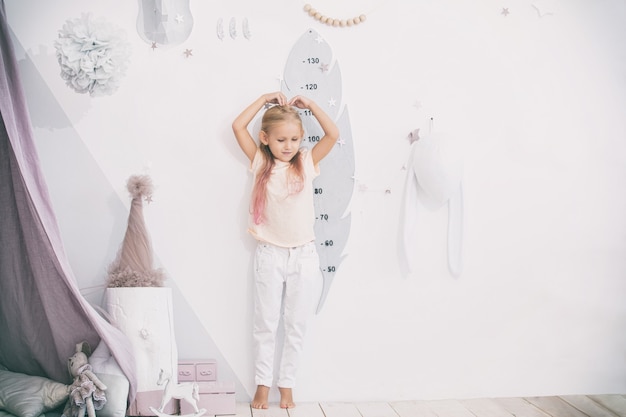 Niña hermosa en la sala de juegos para niños mide su altura