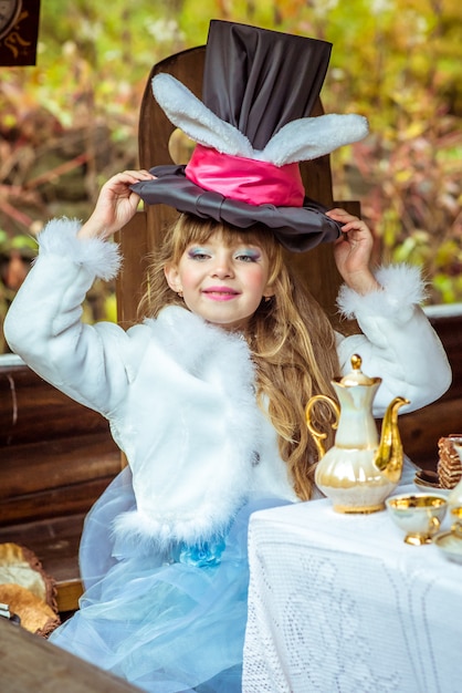 Una niña hermosa con sombrero cilíndrico con orejas como un conejo sobre la cabeza en la mesa