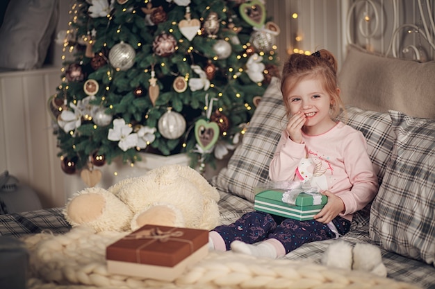 Niña hermosa con sus regalos se sienta en su cama