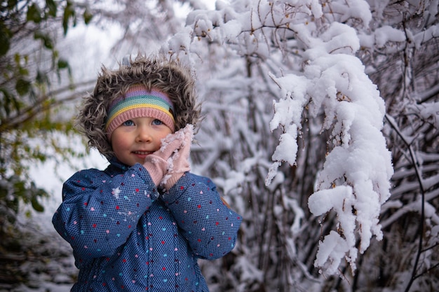 Una niña hermosa vestida de invierno parada sola en medio de un bosque nevado