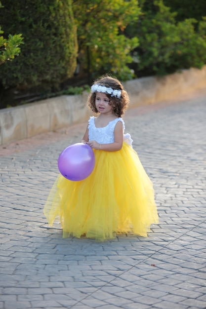 Niña hermosa con un vestido amarillo en un parque de la casa de campo al aire libre fondo de verano