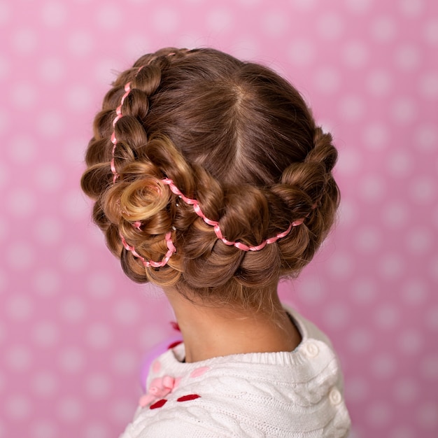 Niña con hermoso peinado sobre fondo rosa