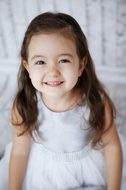 Niña en un hermoso vestido blanco sobre un fondo de madera clara