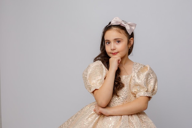 Niña con un hermoso vestido sobre un fondo blanco.