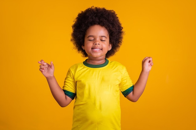 Niña hincha de fútbol brasileño con los dedos cruzados animando a brasil