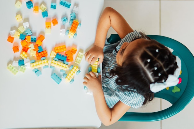 Niña hispana preescolar jugando con bloques de colores en un jardín de infantes