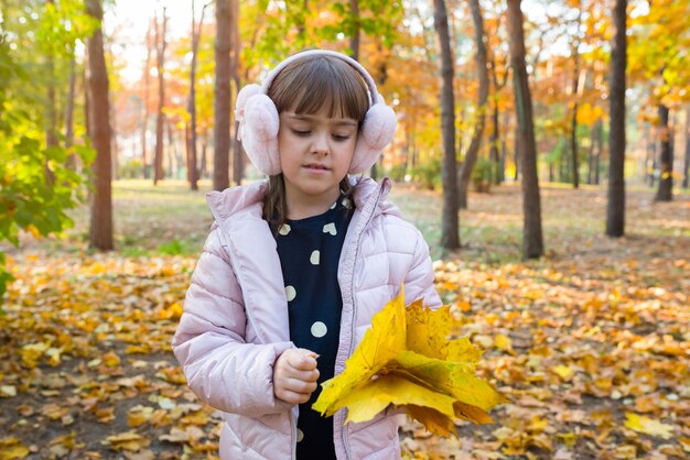 Niña con hojas de arce amarillas en el parque soleado de otoño concepto de estilo de vida de infancia feliz