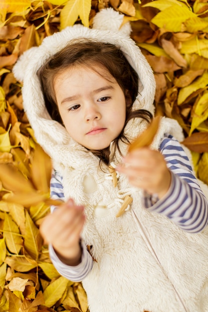 Niña en las hojas de otoño