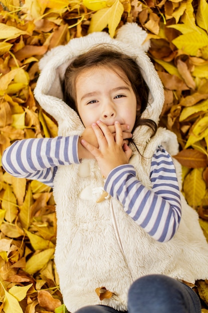 Niña en las hojas de otoño