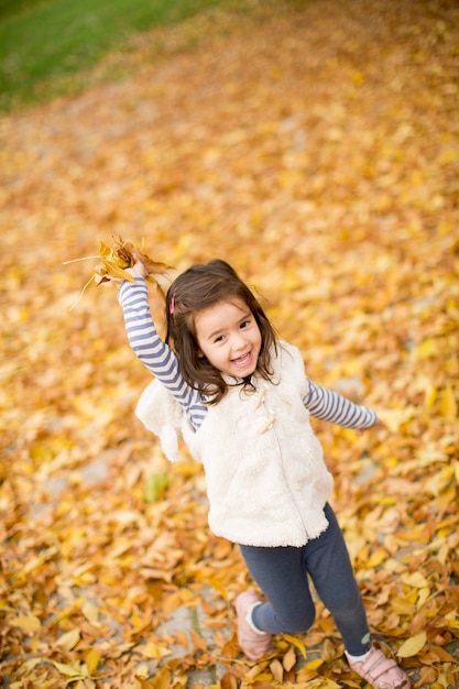 Niña en las hojas de otoño