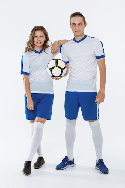 Foto niña y hombre con uniformes de fútbol sosteniendo una pelota de fútbol en un fondo blanco