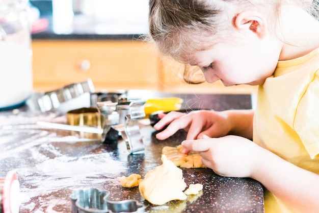 Niña horneando galletas de azúcar en la cocina.