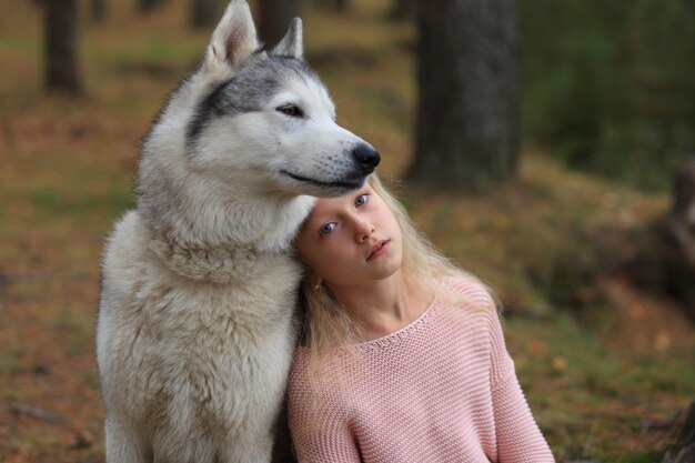 Una niña con un husky camina en el bosque.