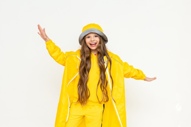 Una niña con un impermeable ha extendido los brazos en diferentes direcciones y sonríe ampliamente Un niño con un impermeable amarillo y un sombrero panamá sobre un fondo blanco aislado