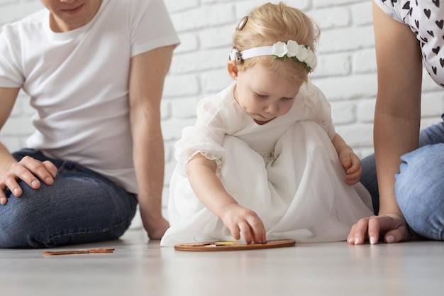 Niña con implante coclear juega en casa con madre y padre escucha discapacidad y diversidad