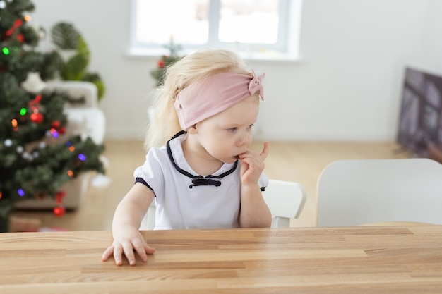 Niña con implantes cocleares divirtiéndose en casa con audífonos de fondo de árbol de navidad y tecnologías innovadoras para el tratamiento de la sordera