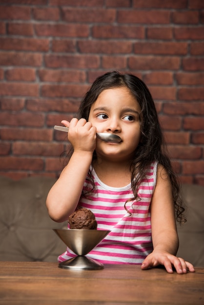 Niña india comiendo helado en un recipiente