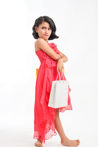 Niña india feliz sosteniendo bolsas de compras sobre fondo blanco.