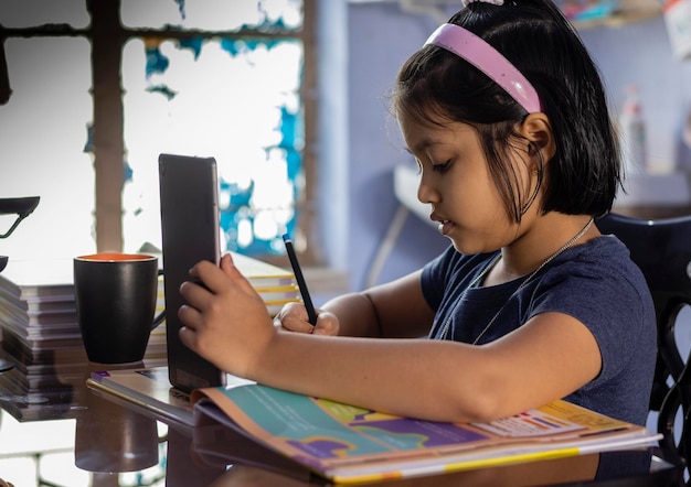 Una niña india linda estudiando en casa con una tableta