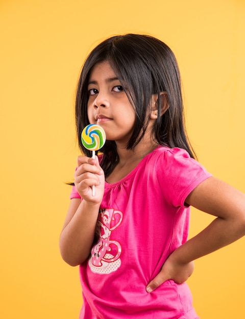 Niña india con lolipop o loly pop, chica asiática y lolipop o lolypop, juguetona linda chica india posando con lolipop o caramelo