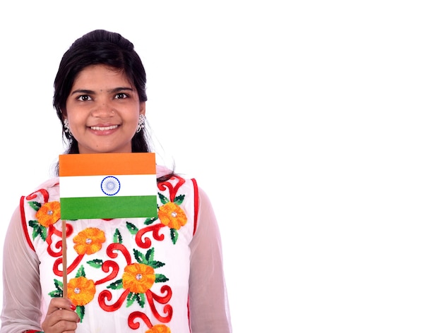 Niña india de pie con bandera india o tricolor sobre fondo blanco.