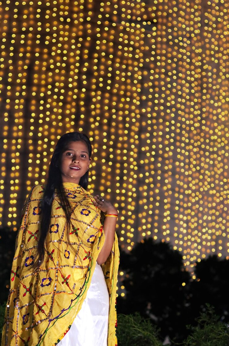 Niña india de pie frente a las luces de la decoración de Diwali borrosas en el fondo