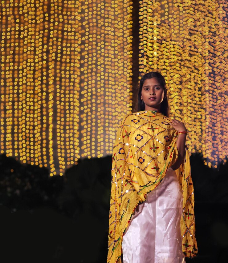 Niña india de pie frente a las luces de la decoración de Diwali borrosas en el fondo