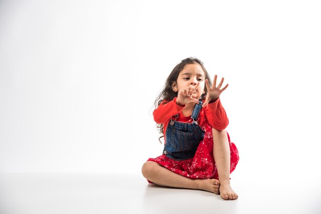 Niña india sentada sobre un piso blanco