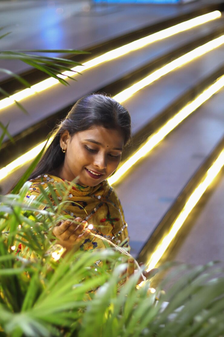 Niña india sonriendo en las escaleras decoradas con luces de fantasía en la planta decorada para Diwali