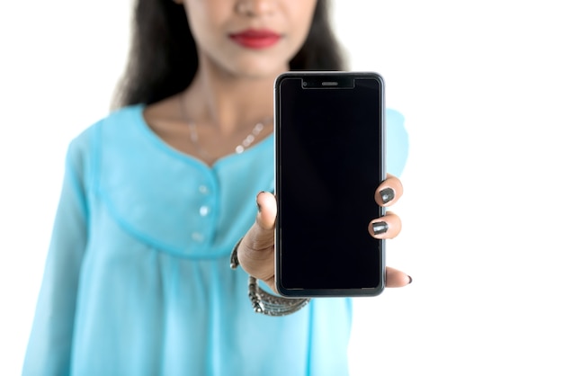 Niña india con un teléfono móvil o un smartphone aislado sobre un fondo blanco.