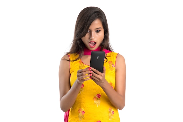 Niña india con un teléfono móvil o un smartphone aislado