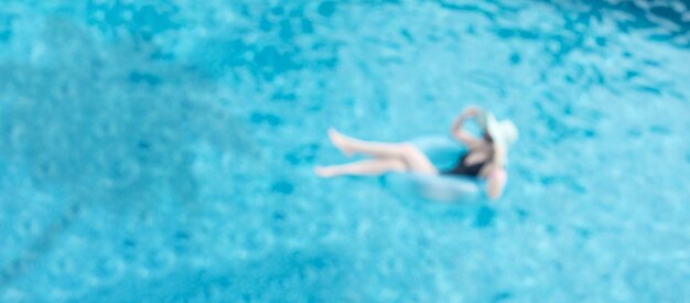 Niña en inflatable azul en la piscina disfrutando de sus vacaciones acostada en el anillo de la piscina