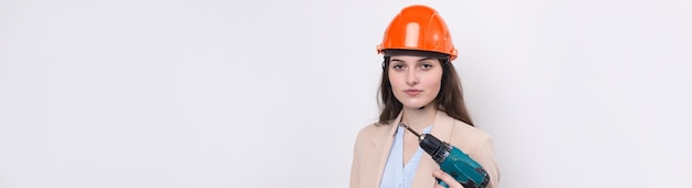 Niña ingeniera en un casco de construcción naranja con un destornillador y un martillo en un fondo blanco