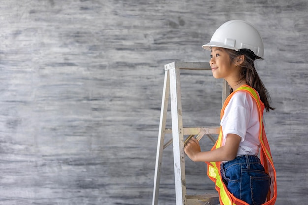 Niña ingeniera usa camisa de seguridad y herramienta de sujeción de casco de seguridad en el sitio de construcción Concepto de aprendizaje y trabajo de ensueñox9