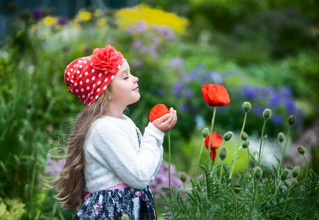 niña inhala el aroma de una flor en el jardín.