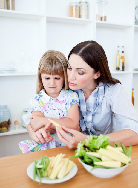 Niña insatisfecha comiendo verduras con su madre