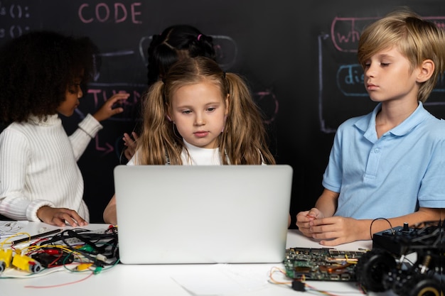 Niña inteligente con babero blanco aprendiendo tecnología robótica usando computadora portátil Erudición