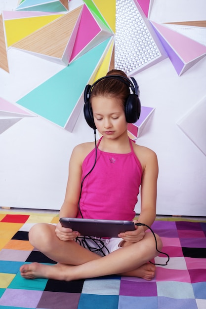 Niña inteligente con una tableta en una sala de estudio.