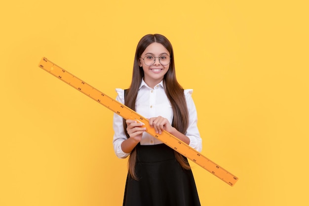 Niña interpolada sonriente sostenga la regla de regreso a la escuela álgebra y geometría niño en gafas estudiar matemáticas