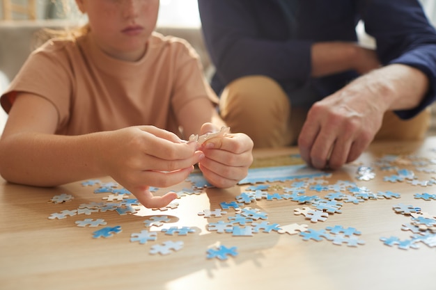 Niña irreconocible jugando juegos de mesa con los abuelos mientras disfruta del tiempo juntos