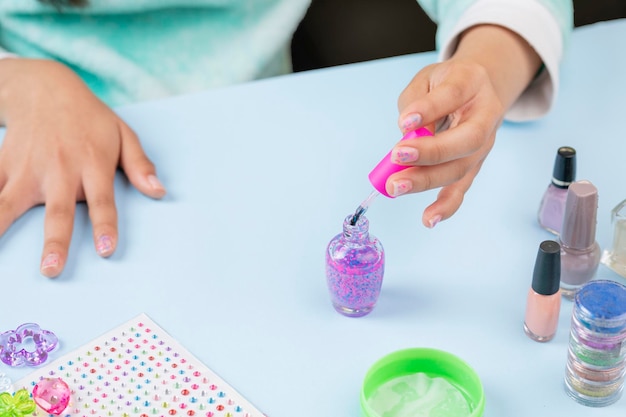 Niña irreconocible se pinta las uñas con barniz en casa